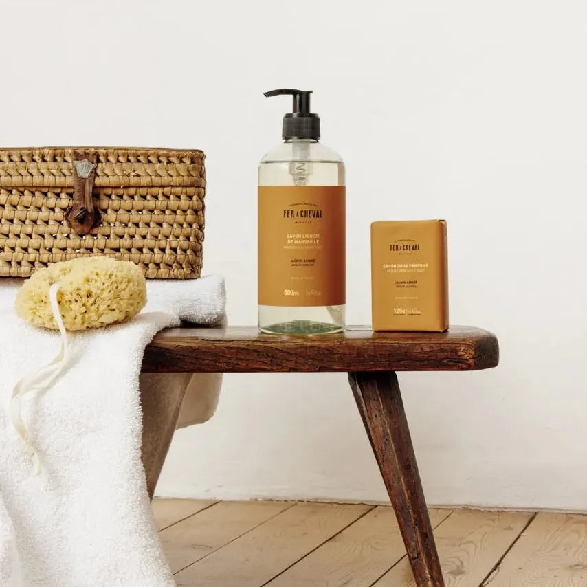 Bathroom setting with a wooden bench, bath products, and a white towel.