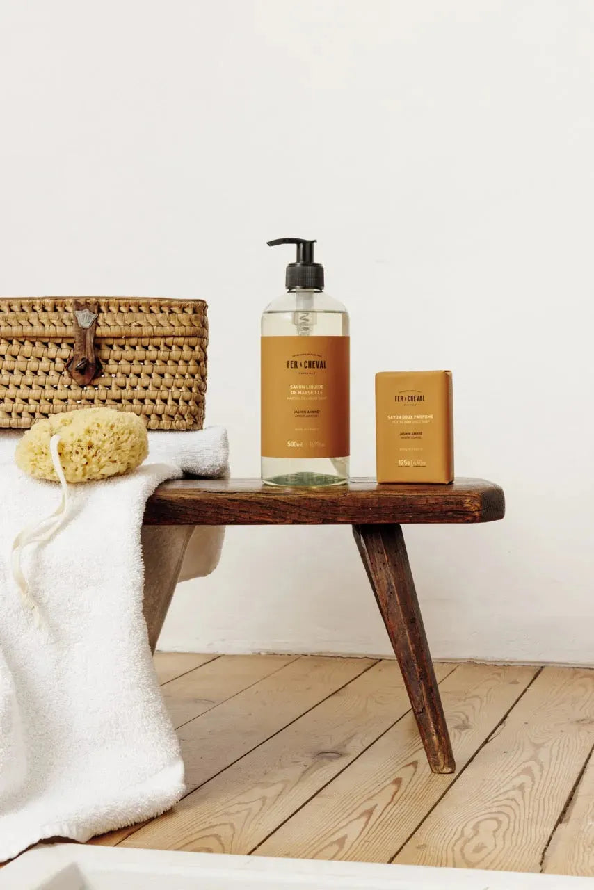 Bathroom setting with a wooden bench, bath products, and a white towel.