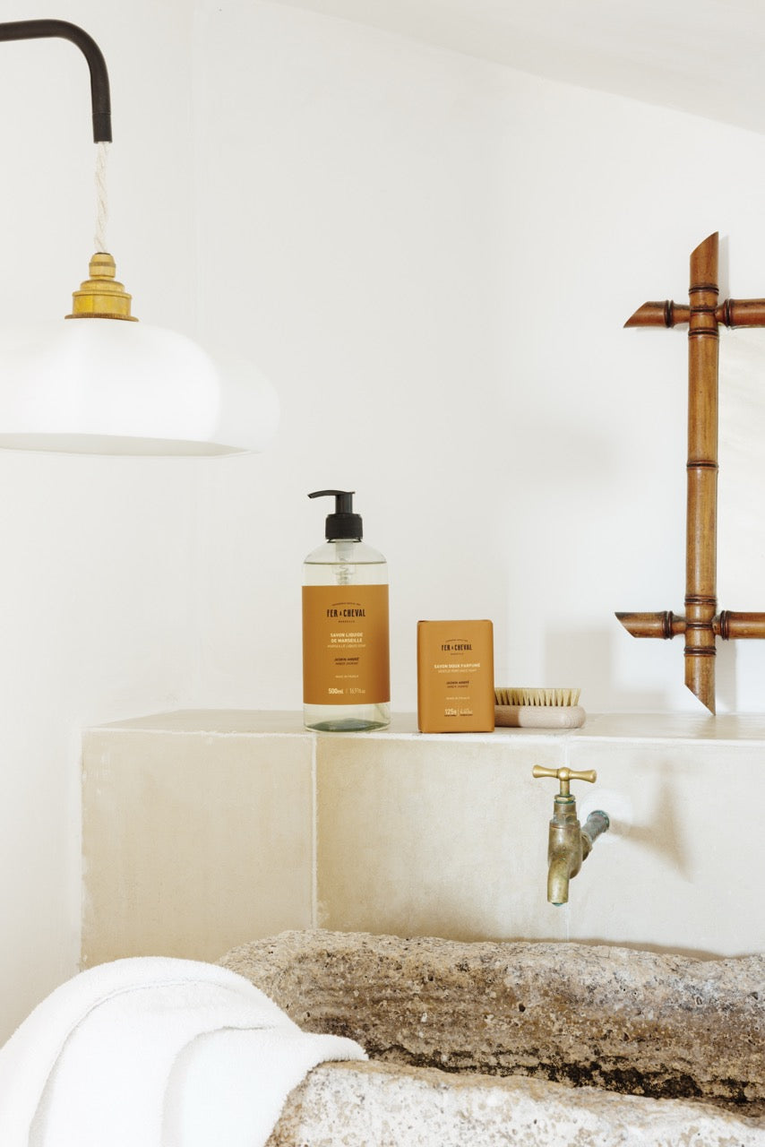 Bathroom setting with a sink, faucet, and toiletries on a white countertop.