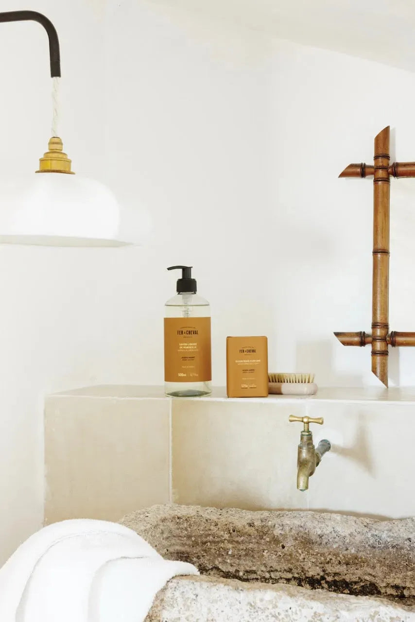 Bathroom setting with a sink, faucet, and toiletries on a white countertop.