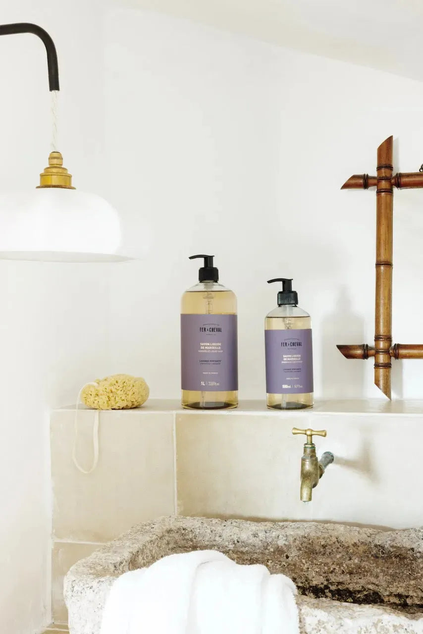 Bathroom setting with two bottles of soap on a shelf, a faucet, and a towel.