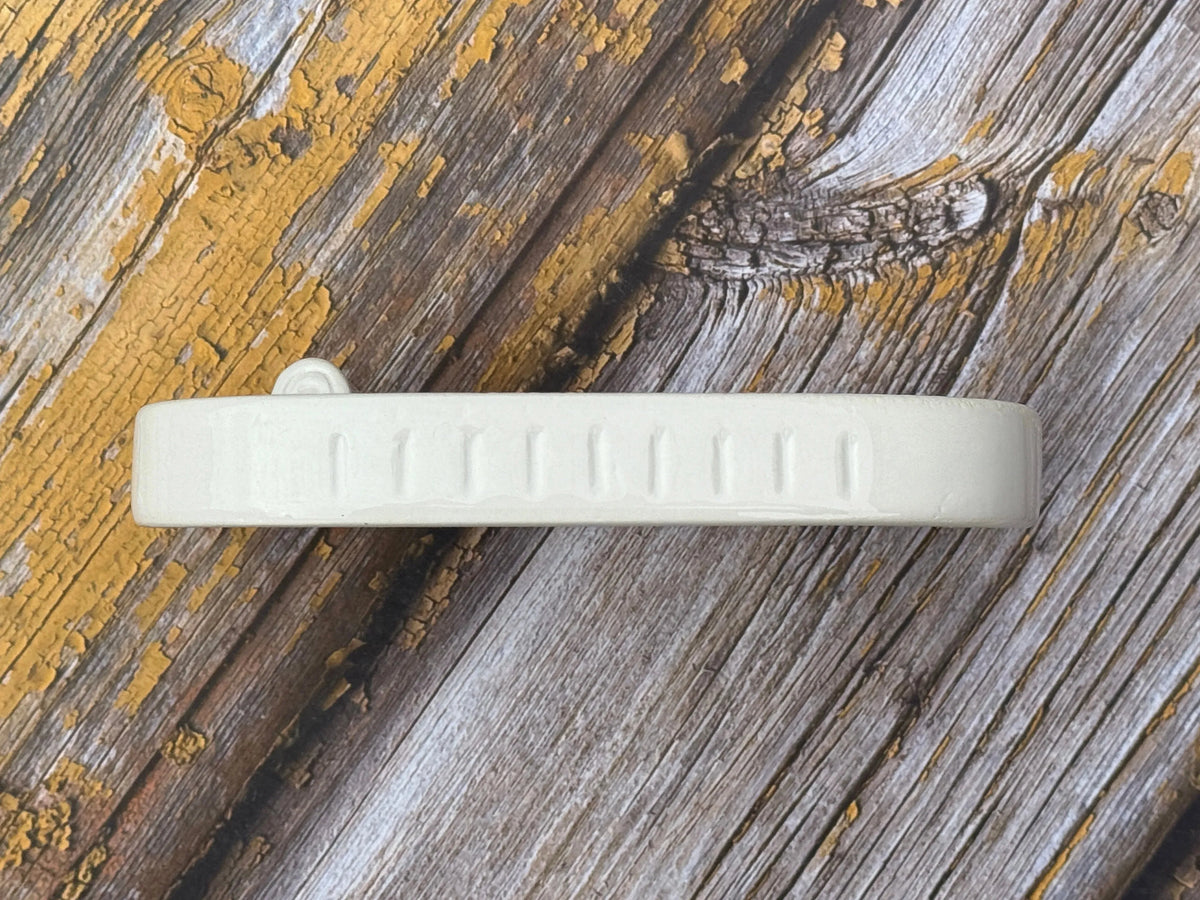Side of a ceramic soap dish on a wooden table top