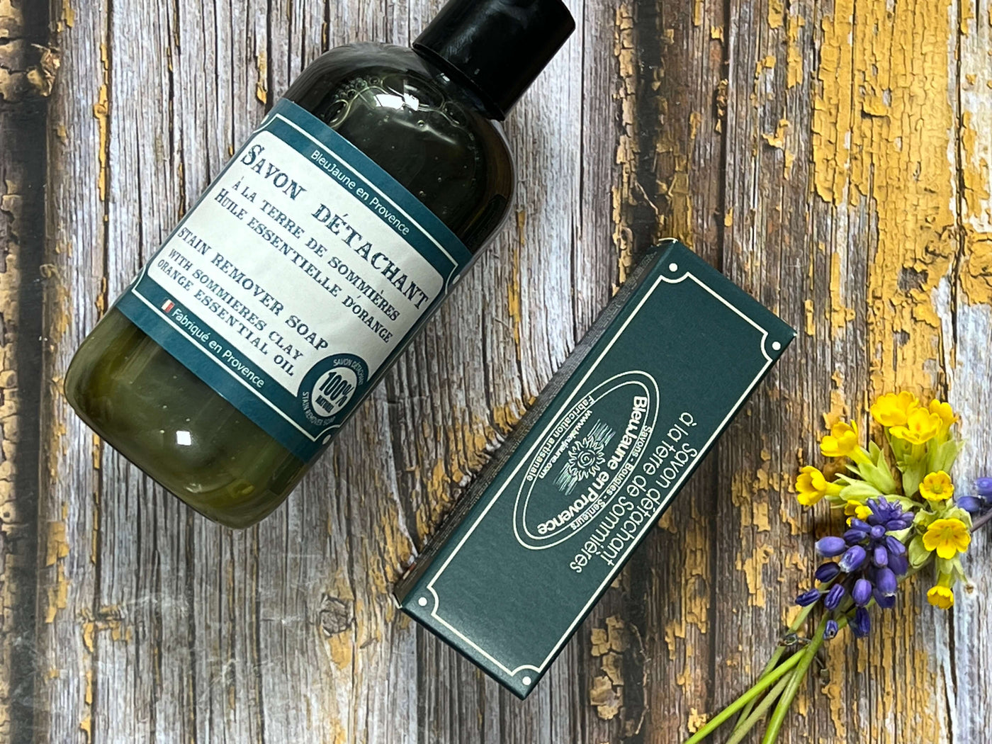 Bottle and box of soap on a wooden surface with flowers