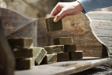 A hand picking up an olive oil soap