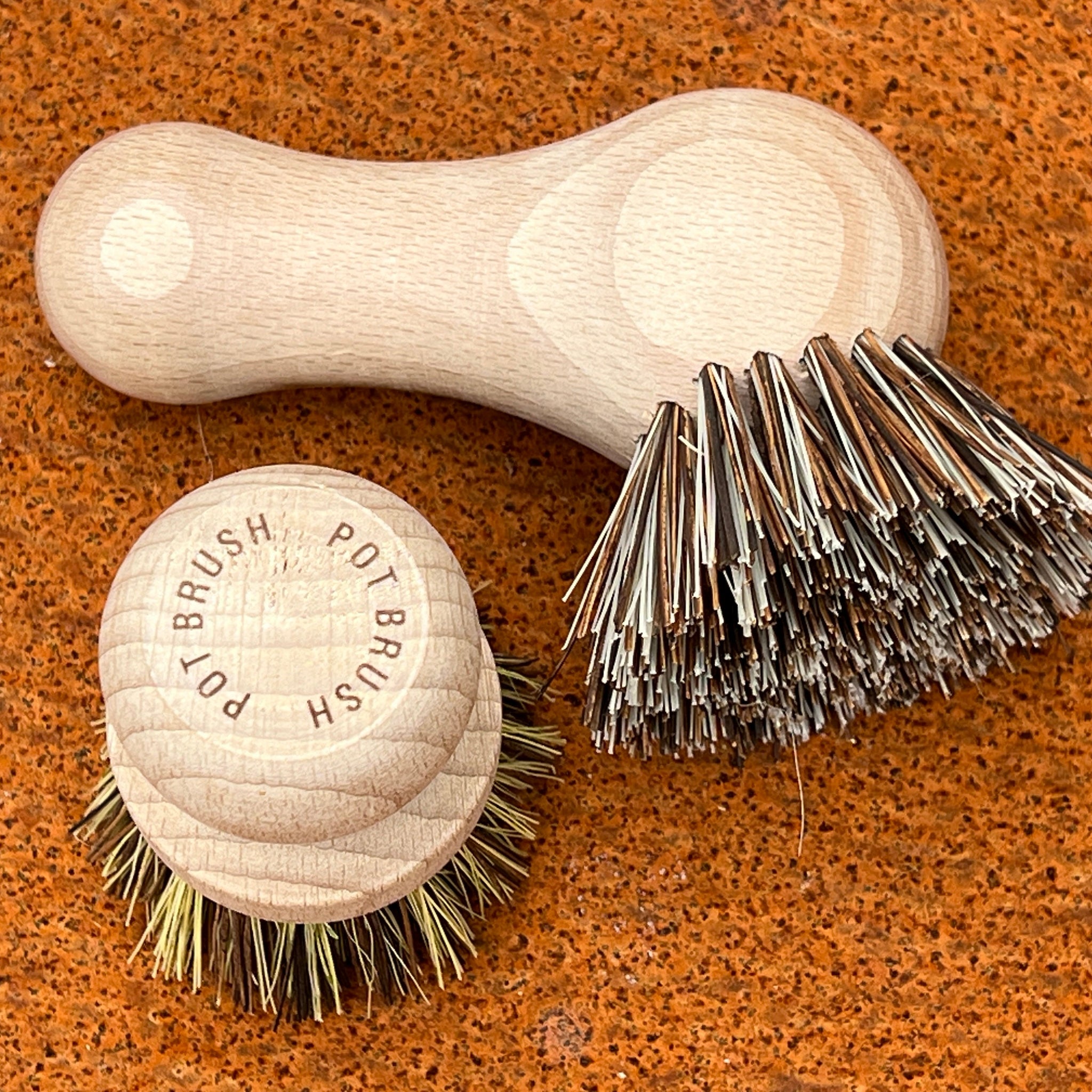 two pot brushes on an textrued orange background