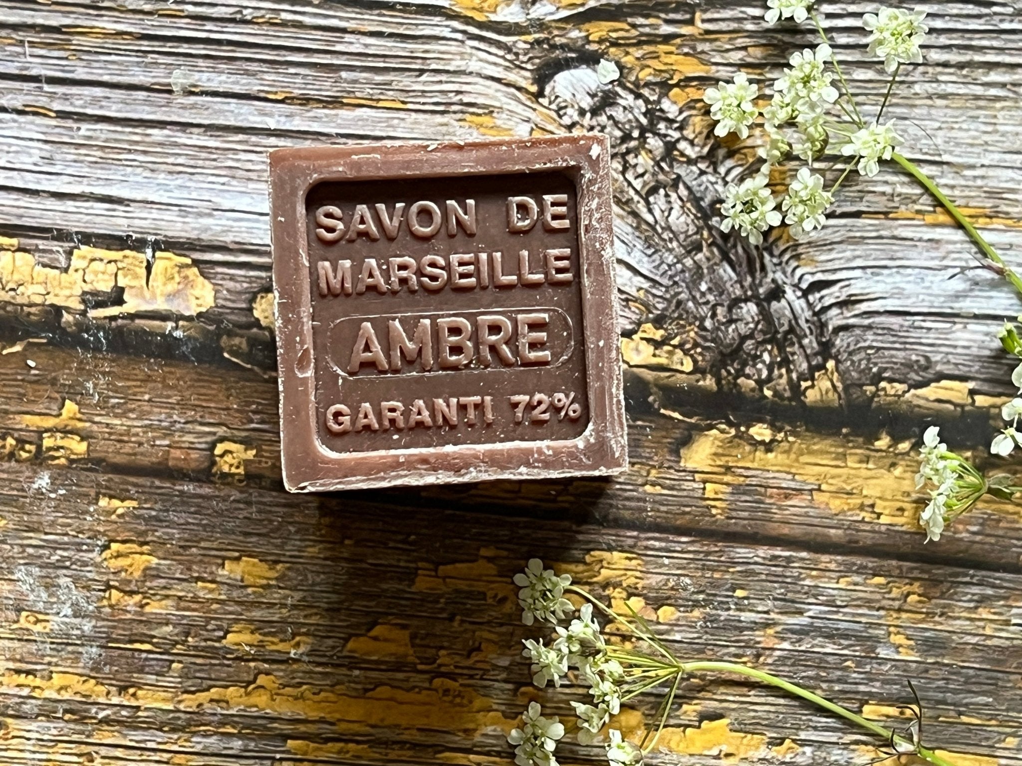 A Cube of Brown Amber Franced Savon de Marseille on a Wooden Table.