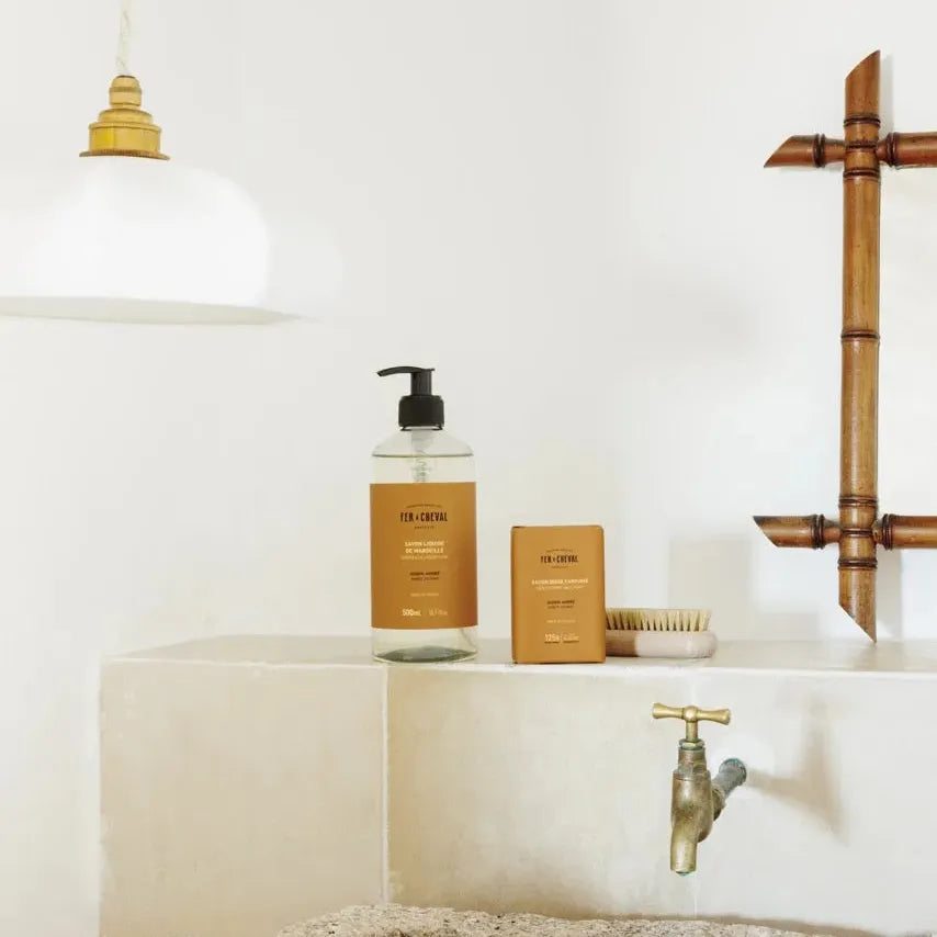 Bathroom setting with a sink, faucet, and toiletries on a white countertop.