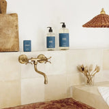 Bathroom with marble countertop, brass faucet, and toiletries.