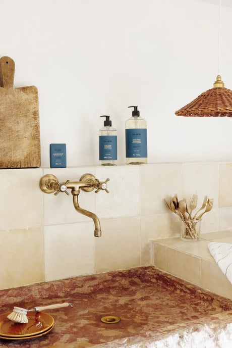 Bathroom with marble countertop, brass faucet, and toiletries.