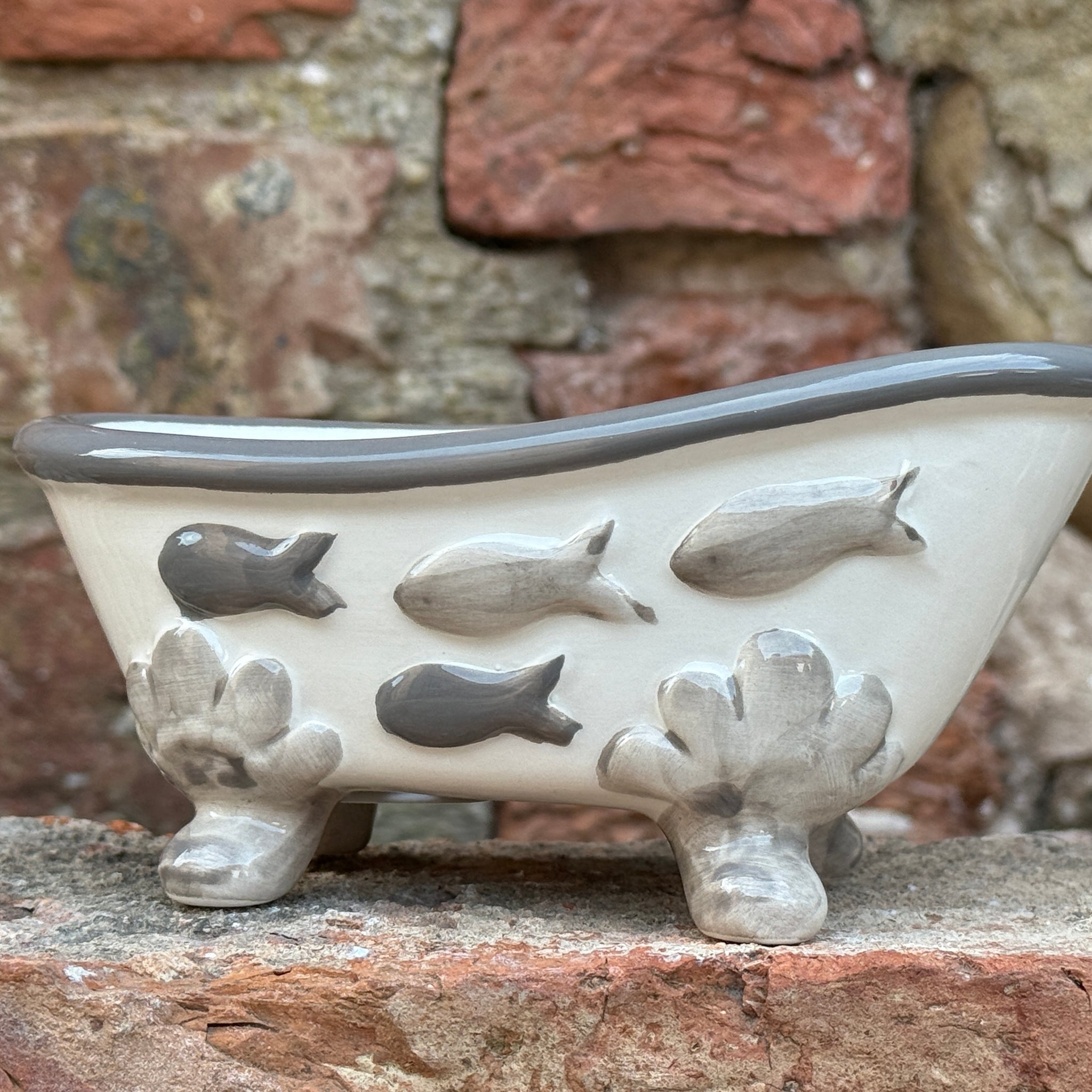 Ceramic bathtub with fish designs on a stone surface