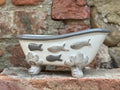 Ceramic bathtub with fish designs on a stone surface