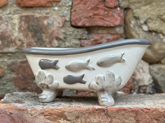 Ceramic bathtub with fish designs on a stone surface