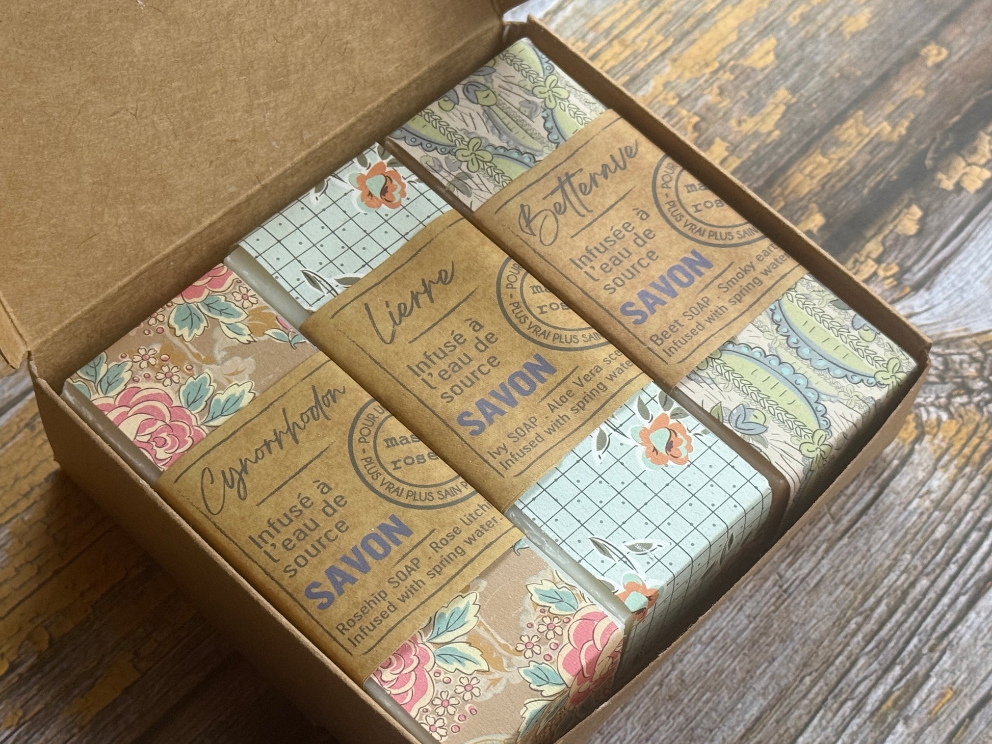 Box of soap bars with decorative packaging on a wooden surface