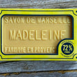 Bar of soap with 'Savon de Marseille Madeleine' packaging on a wooden surface