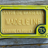 Bar of soap with 'Savon de Marseille Madeleine' packaging on a wooden surface