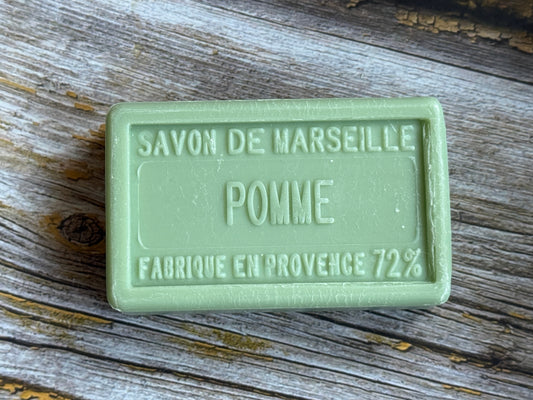 Green soap bar labeled 'Savon de Marseille Pomme' on a wooden surface