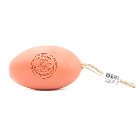 Pink bar of soap with a string on a white background