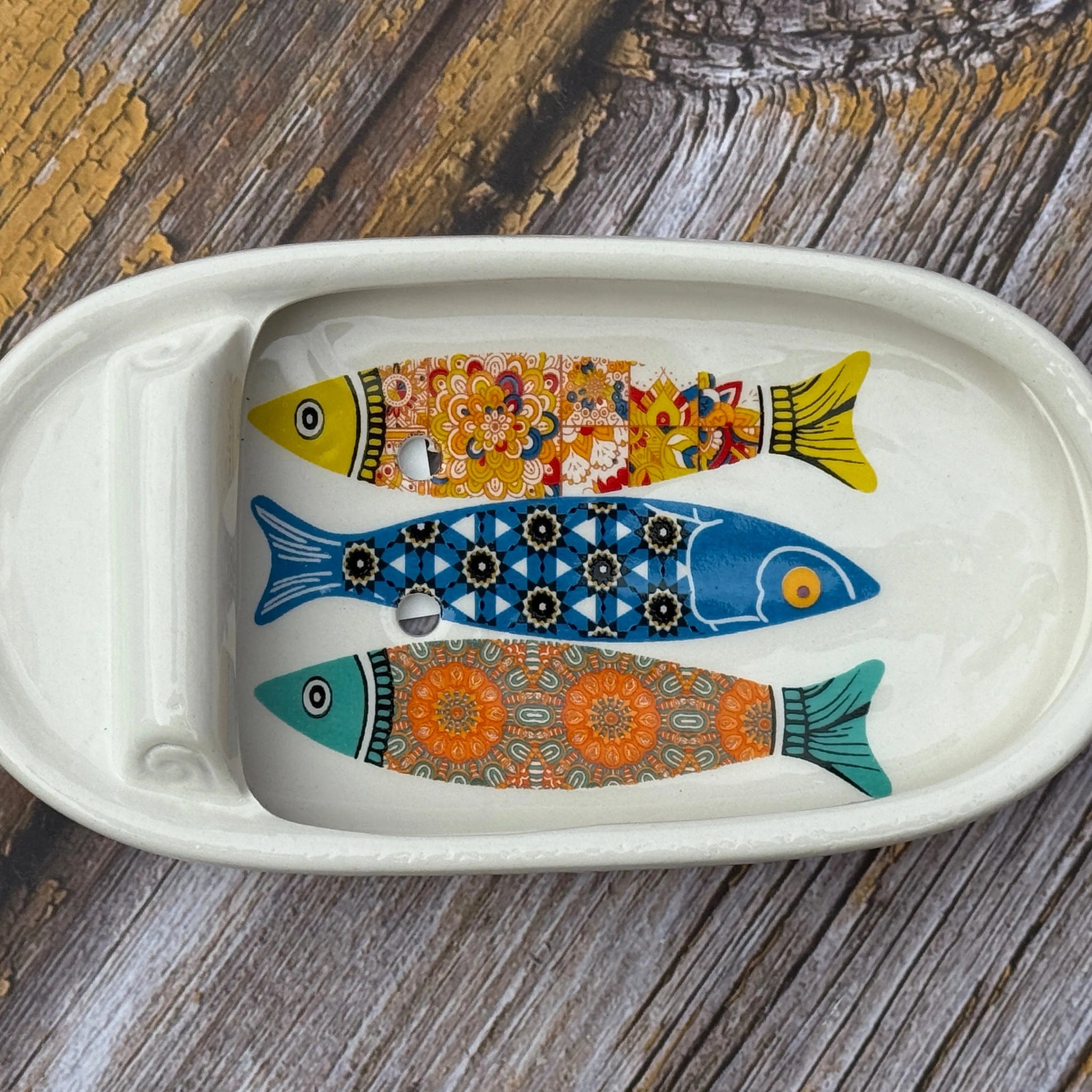 Decorative ceramic tray with fish designs on a wooden surface