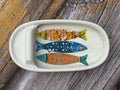 Decorative ceramic tray with fish designs on a wooden surface