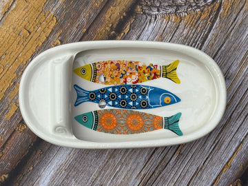 Decorative ceramic tray with fish designs on a wooden surface