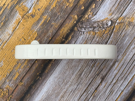 Side of a ceramic soap dish on a wooden table top