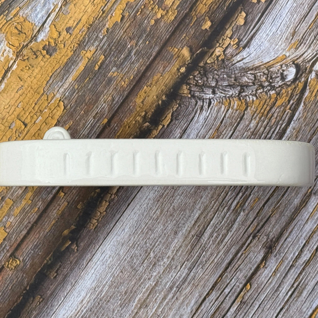 Side of a ceramic soap dish on a wooden table top