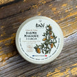 A tub of balm on a wooden surface