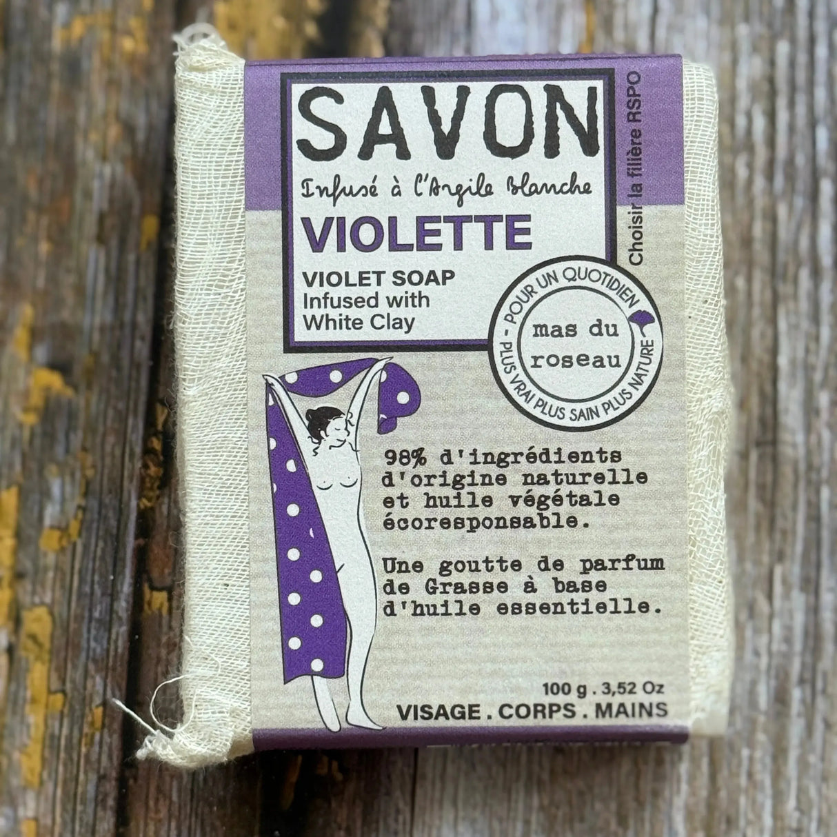 violet Bar of violet soap with packaging on a wooden surface
