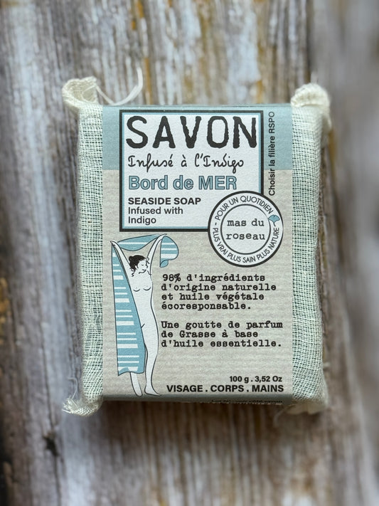 Bar of soap with packaging labeled 'Savon' on a wooden background