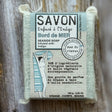Bar of soap with packaging labeled 'Savon' on a wooden background