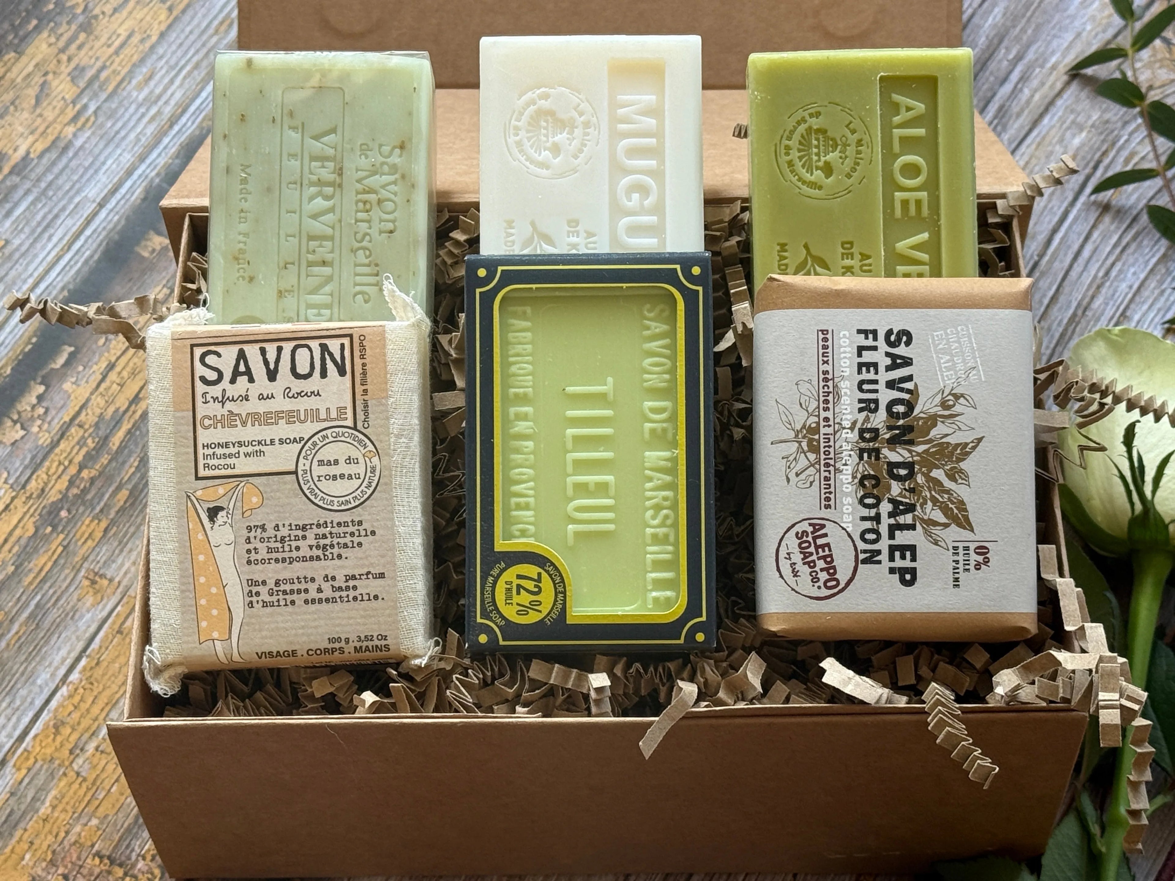 A selection of Green and White Fragranced soaps in a kraft box on a wooden background
