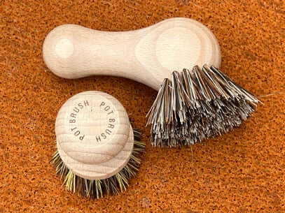 Two brushes with different bristle types on a corten steel surface