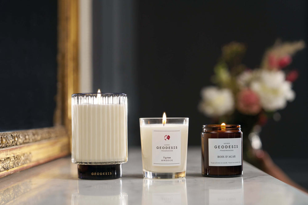Three Geodesis candles on a table with a dark background
