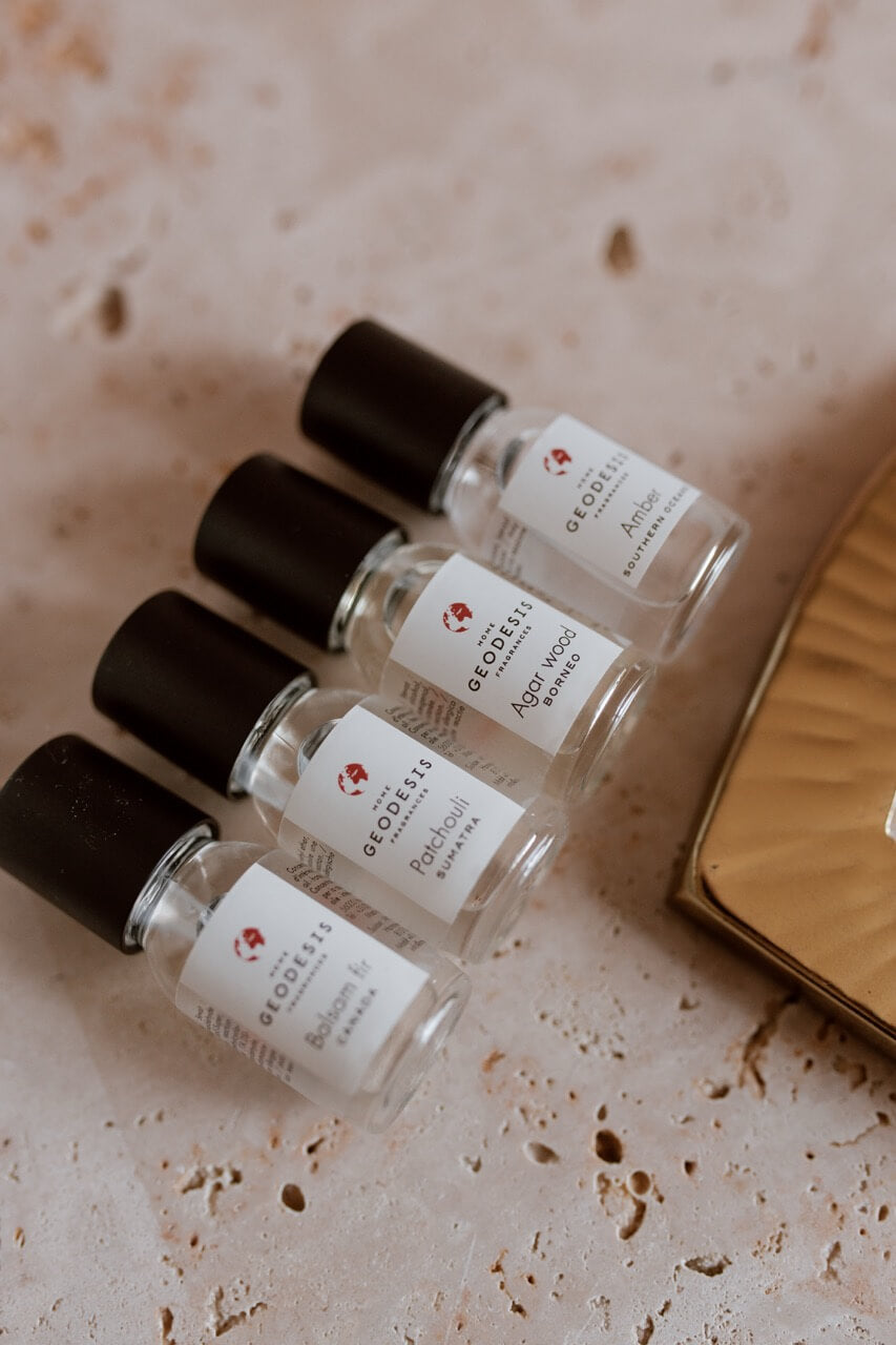 Four small fragrance oil concentrates for electric diffusers  bottles with black caps on a textured surface. French Soaps UK