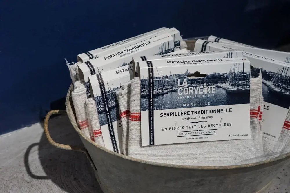 Packages of 'La Corvette' Mop Cloths in a metal container against a blue background