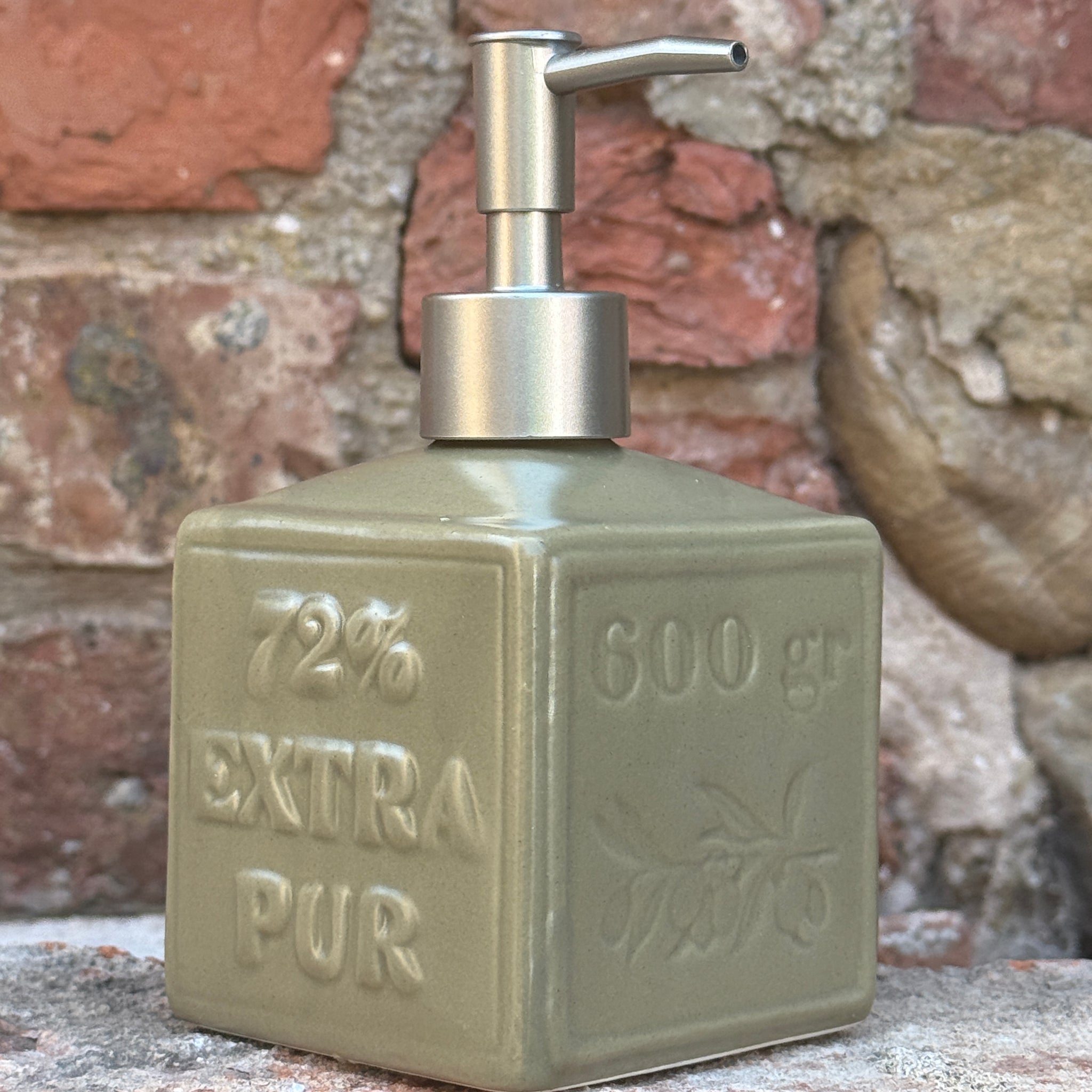 Vintage-style soap dispenser with 'Extra Pur' text on a textured wall background