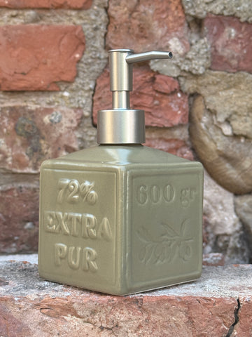 Vintage-style soap dispenser with 'Extra Pur' text on a textured wall background