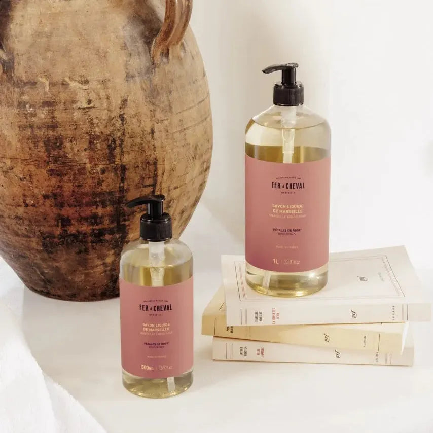 Two bottles of 'Ten Thousand Villages' soap on a white surface with a rustic vase in the background.