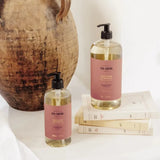 Two bottles of 'Ten Thousand Villages' soap on a white surface with a rustic vase in the background.
