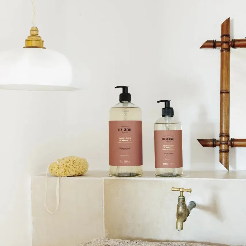 Bathroom setting with bottles on a shelf, faucet, and bath mat.