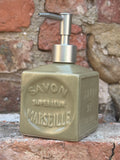 Soap dispenser with 'Savon de Marseille' branding attached to a stone wall.