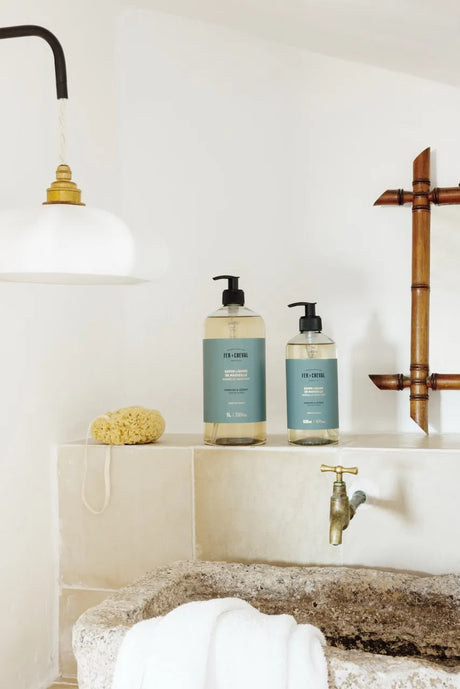Bathroom setting with two bottles of soap on a shelf, a faucet, and a bath mat.