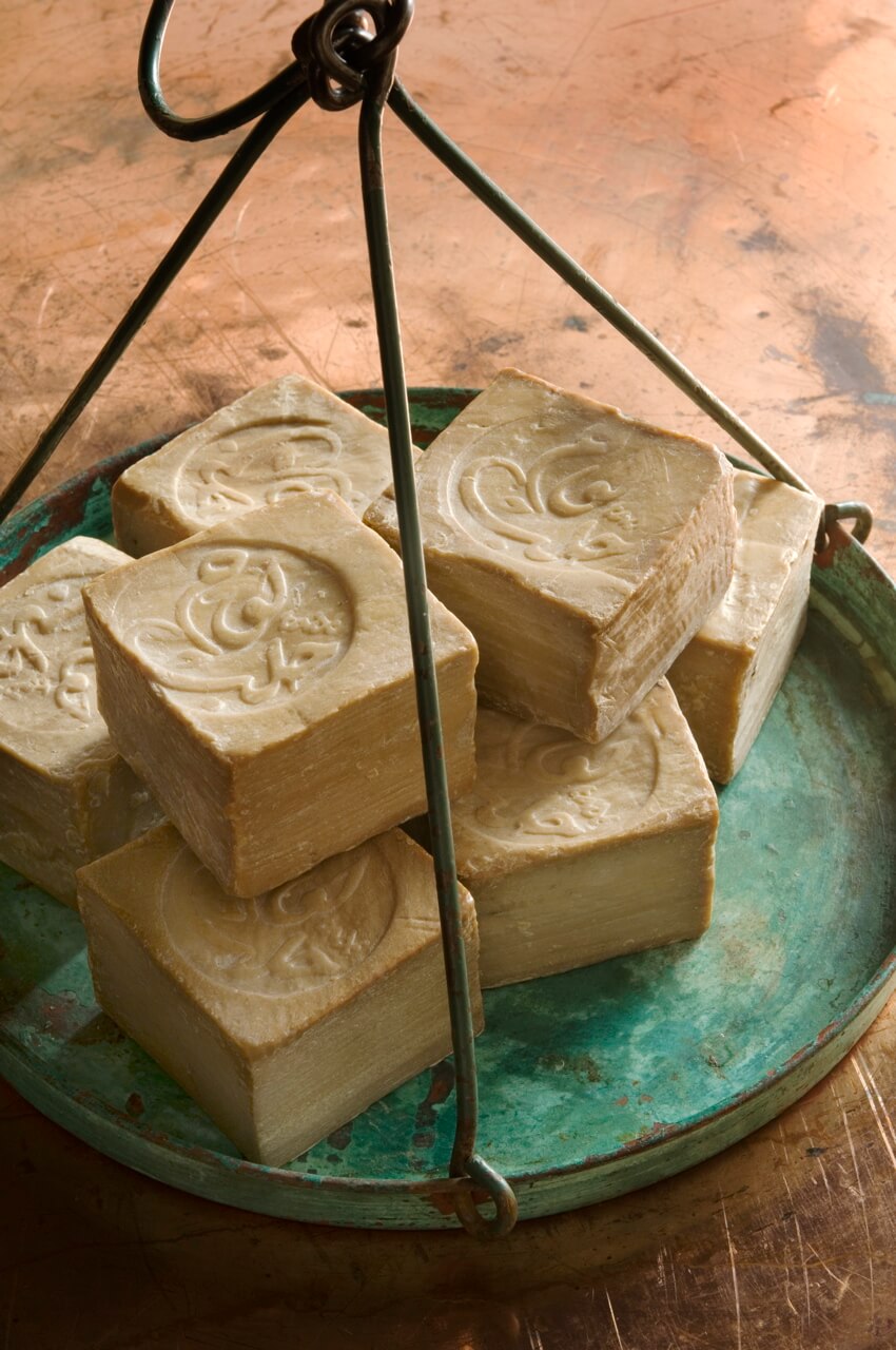 Handmade soap bars with a logo on a rustic metal scale