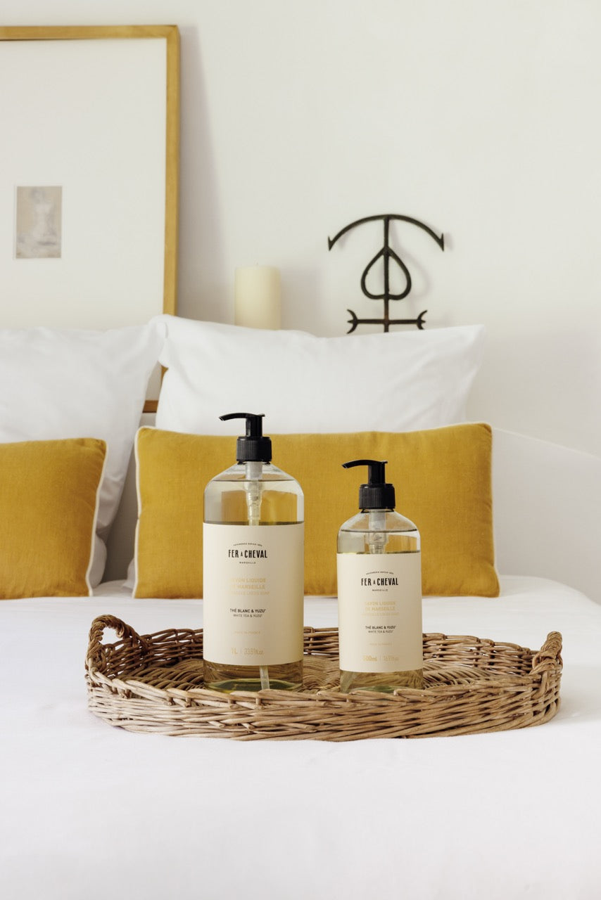 Two bottles of 'Fever-Tree' on a wicker tray with yellow cushions and a white pillow in the background.
