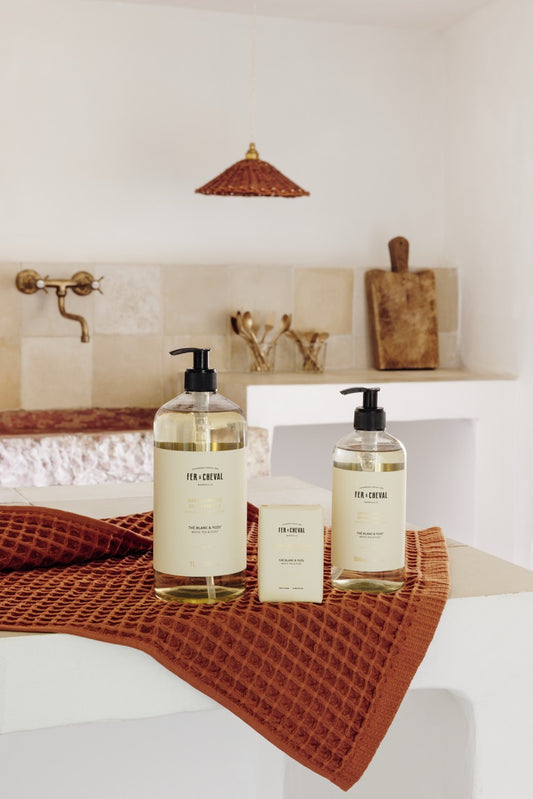 Bath products including bottles and a bar of soap on a towel in a bathroom setting.