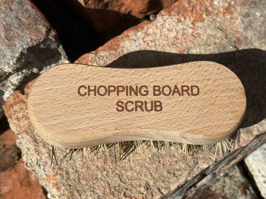 Wooden scrubbing brush with 'Chopping Board Scrub' text on a stone surface