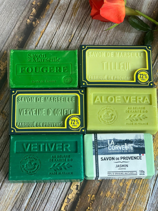 Collection of Marseille soap bars with various scents on a wooden surface.