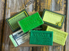 Collection of green soap bars with various labels on a wooden surface