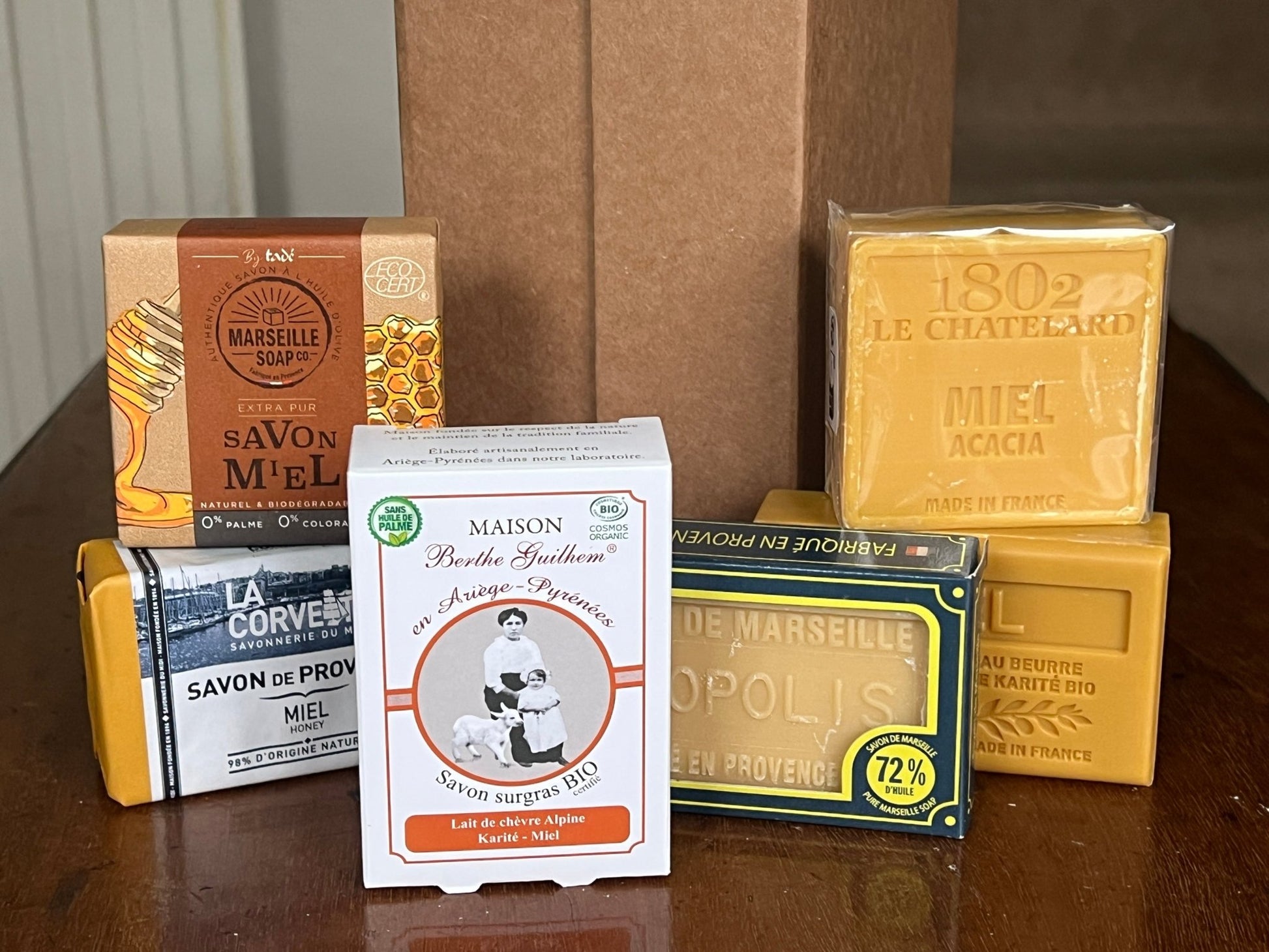 Collection of various Honey Savon de Marseille soaps and packaging on a wooden surface