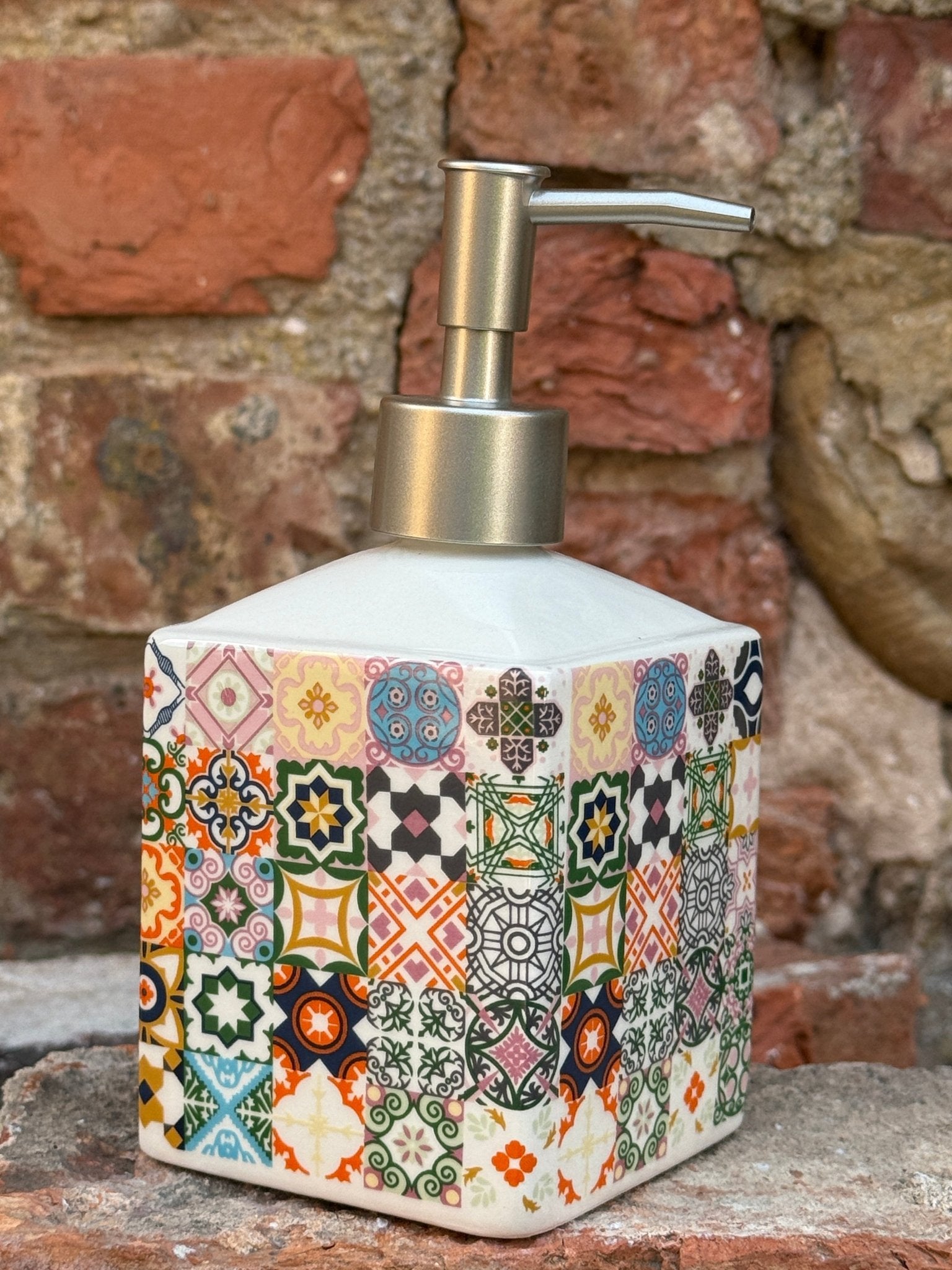Decorative soap dispenser with colorful pattern on a brick wall background


